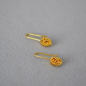 Detailed close-up of gold-plated pinecone earrings showing delicate texture and long hooks