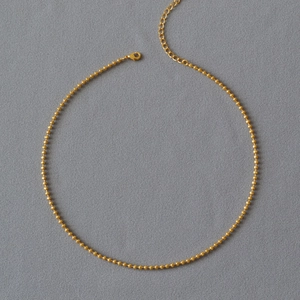Detailed view of a gold-plated brass ball chain necklace with adjustable lobster clasp