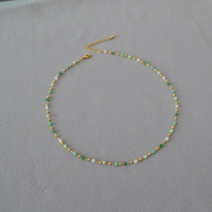 Detail of gradient green and white beaded necklace with gold lobster clasp and extension