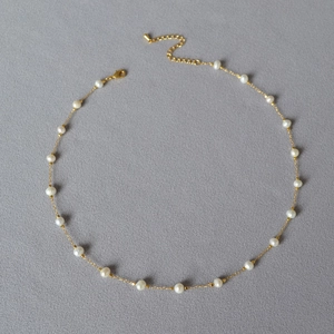 Detailed view of irregular baroque pearls on a slim gold plated brass chain necklace