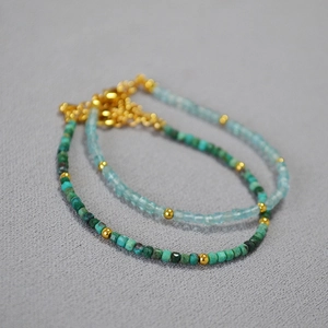 Detailed macro of minimalist turquoise and blue crystal bead bracelets with gold accents