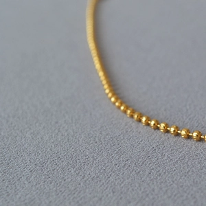 Macro shot of gold bead chain with faceted texture showcasing refined craftsmanship
