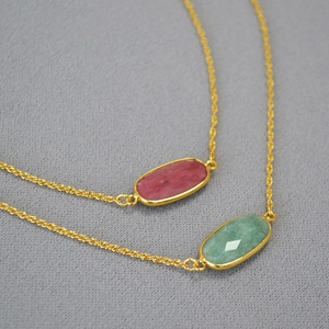 Detail of oval pink and green gemstone necklaces with golden brass rope chains