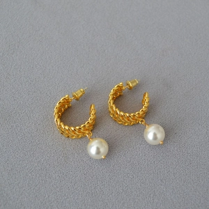 Detail of gold twisted rope hoop earrings featuring white round pearl drops
