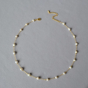 Macro detail of gold plated brass necklace with evenly spaced white freshwater pearls