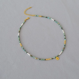 Macro shot of turquoise beads necklace with golden evil eye pendant and lobster clasp