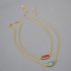 Detail of faceted oval stone pendants with gold plated chains and lobster clasp
