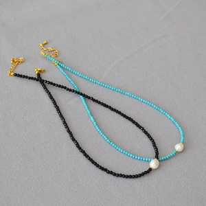 Close-up of handmade beaded necklaces with black spinel, turquoise, and baroque pearls