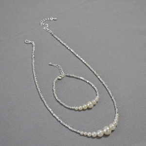 Detailed close-up of irregular silver-toned chain jewelry set with gradient white pearls