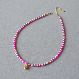 Collier de perles roses et blanches avec pendentif étoile dorée et détail de pierre