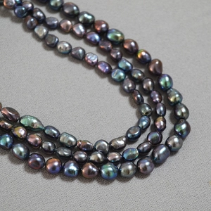 Macro shot of triple-layer irregular black baroque pearl necklace with peacock green sheen