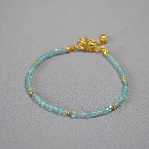 Detail of blue faceted beads and gold spacers on a minimalist beaded bracelet chain