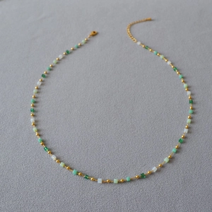 Detail of beaded necklace with gradient green square beads and golden chain link