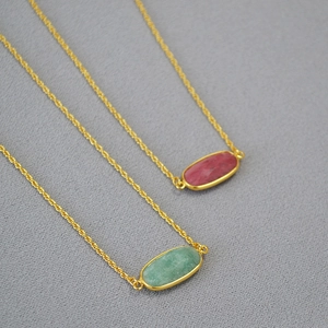 Minimalist gold brass necklaces featuring green and magenta oval gemstone pendants