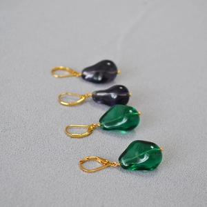 Detail view of emerald and purple glass drop earrings with vintage golden leverback hooks