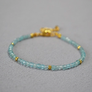 Macro view of blue faceted aquamarine beads and gold spacers on a minimalist beaded bracelet