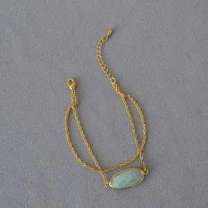 Macro di bracciale a doppia catena dorata con una pietra naturale ovale verde chiaro