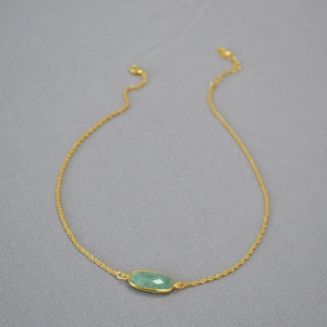 Minimalist gold necklace featuring a faceted green oval stone pendant on a curb chain