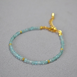 Detail of light blue square beads and gold spacers on a minimalist adjustable bracelet