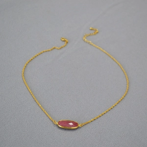 Detail view of gold-plated rope chain necklace with a faceted pink stone pendant