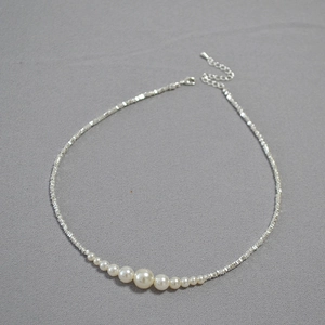 Detailed view of silver irregular beads and gradient white pearls on necklace