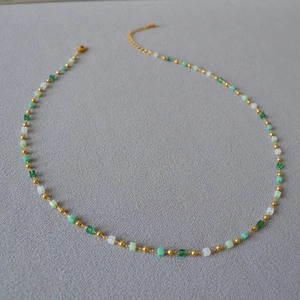 Macro view of green gradient beaded necklace with golden accents and lobster clasp
