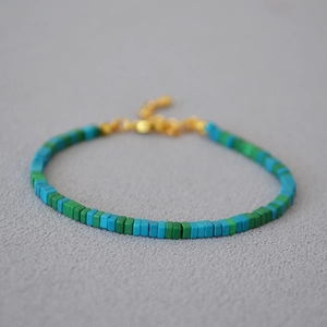 Close-up of moss green and turquoise square beads with gold lobster clasp on beaded bracelet