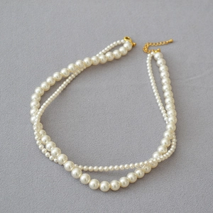 Close-up of double-layered pearl necklace featuring varied sizes with adjustable gold clasp