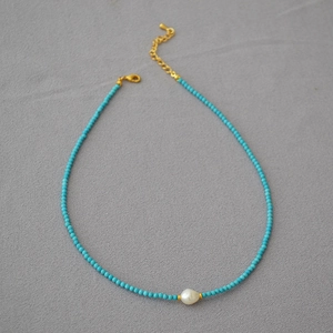 Detail of turquoise beaded necklace featuring a white baroque pearl and gold lobster clasp