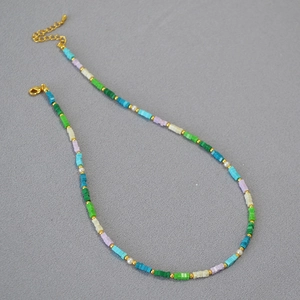 Dettaglio della collana di perline colorate con quadrati turchesi e perle bianche