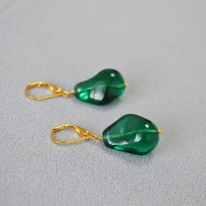 Detailed shot of emerald glass charms on gold leverback earrings with baroque textures