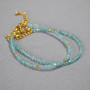 Close-up of minimalist aquamarine beaded bracelet with gold accents and lobster clasp