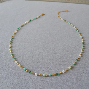 Close-up of green gradient beaded necklace with gold accents and lobster clasp