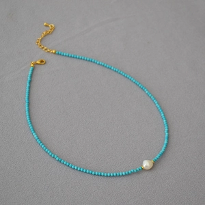Detail of turquoise beaded necklace featuring a white baroque pearl and gold lobster clasp