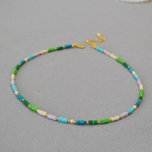 Dettaglio di perline quadrate colorate e finiture dorate su collana fatta a mano