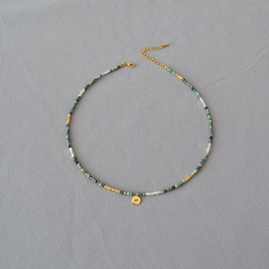Close-up of turquoise beaded necklace with golden evil eye pendant and lobster clasp