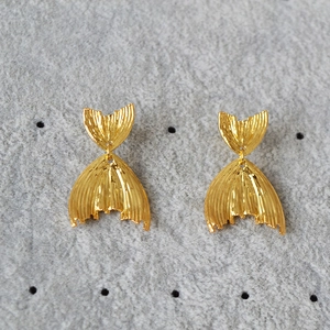 Detail of vintage gold-plated fish tail earrings with fine vertical textures and 925 silver needles