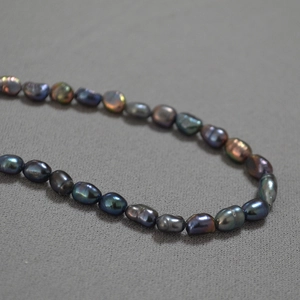 Peacock green Tahitian style baroque pearl necklace with iridescent luster on gray fabric
