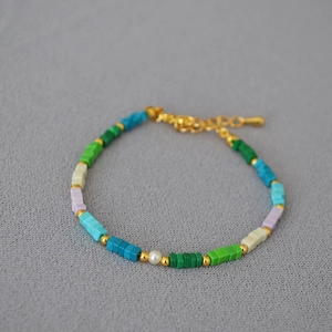 Dettaglio collana con perline quadrate colorate, perla bianca e chiusura dorata