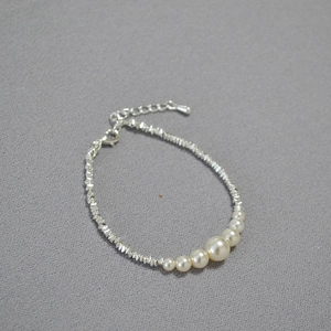 Detailed view of silver bead chain bracelet featuring six graduated white pearls