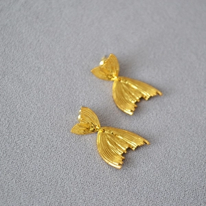 Macro view of gold-plated fishtail earrings with vintage pleated texture and 925 silver pins