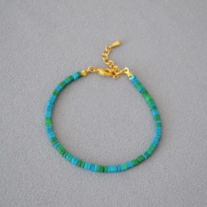 Detailed macro view of green and turquoise beaded bracelet with gold extension chain