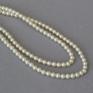 Détail d'un élégant collier de perles crème double couche avec lustre sur tissu gris