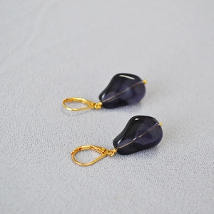 Close-up of teardrop dark purple glass earrings with gold French hook clasps