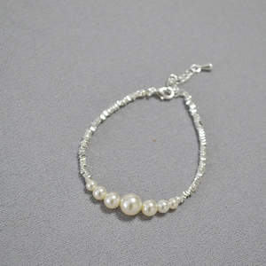 Close-up of irregular silver beads and gradient cream pearls on a delicate necklace