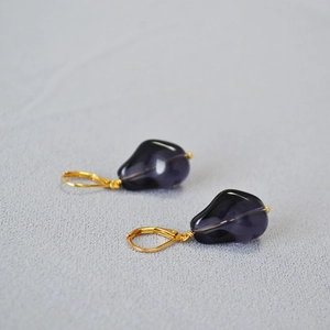 Detailed close-up of dark purple teardrop glass earrings with gold French hook hooks