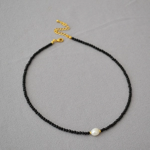 Minimalist black faceted bead necklace featuring a baroque pearl and gold lobster clasp