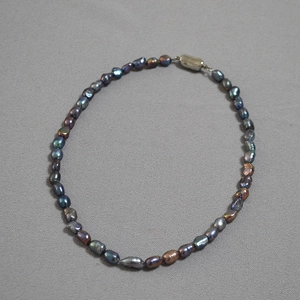 Macro detail of irregular Tahitian green baroque pearls with iridescent luster and silver clasp
