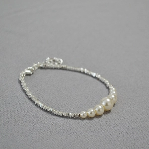 Detail of irregular silver beads and five gradient pearls on a minimalist necklace