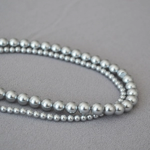 Close-up of double-layered silver-grey pearl necklace with high metallic luster on fabric